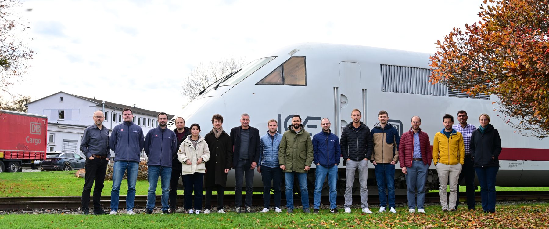 Teilnehmende des Seminars Festigkeit posieren für ein Foto und stehen vor einem ICE