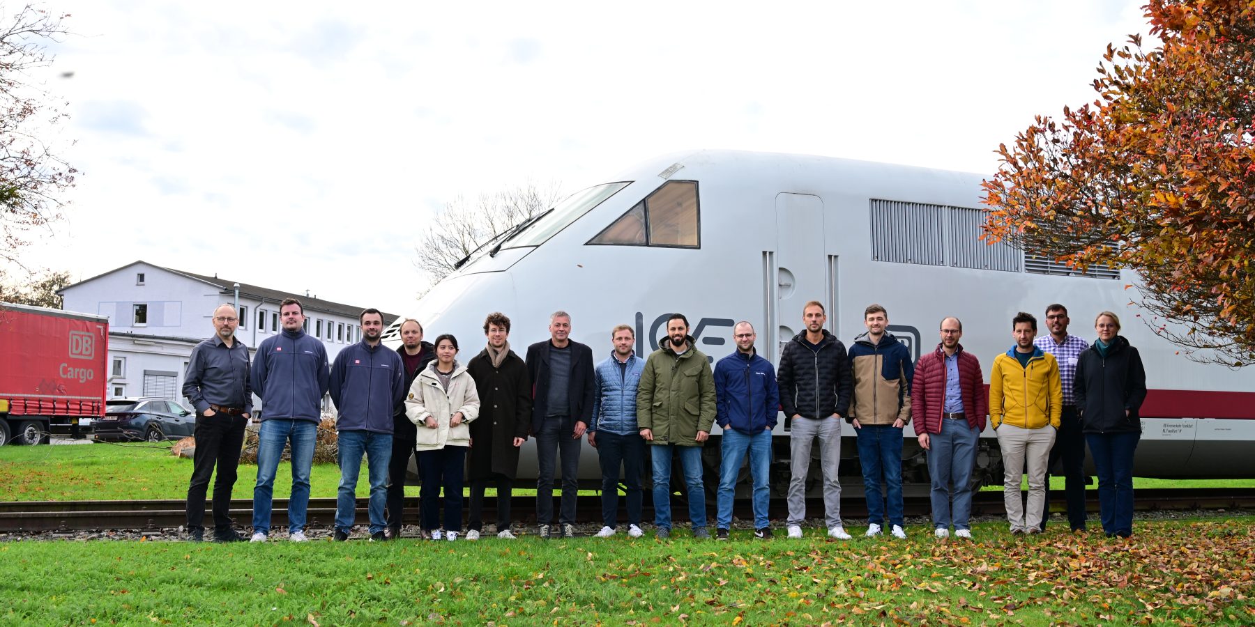 Teilnehmende des Seminars Festigkeit posieren für ein Foto und stehen vor einem ICE