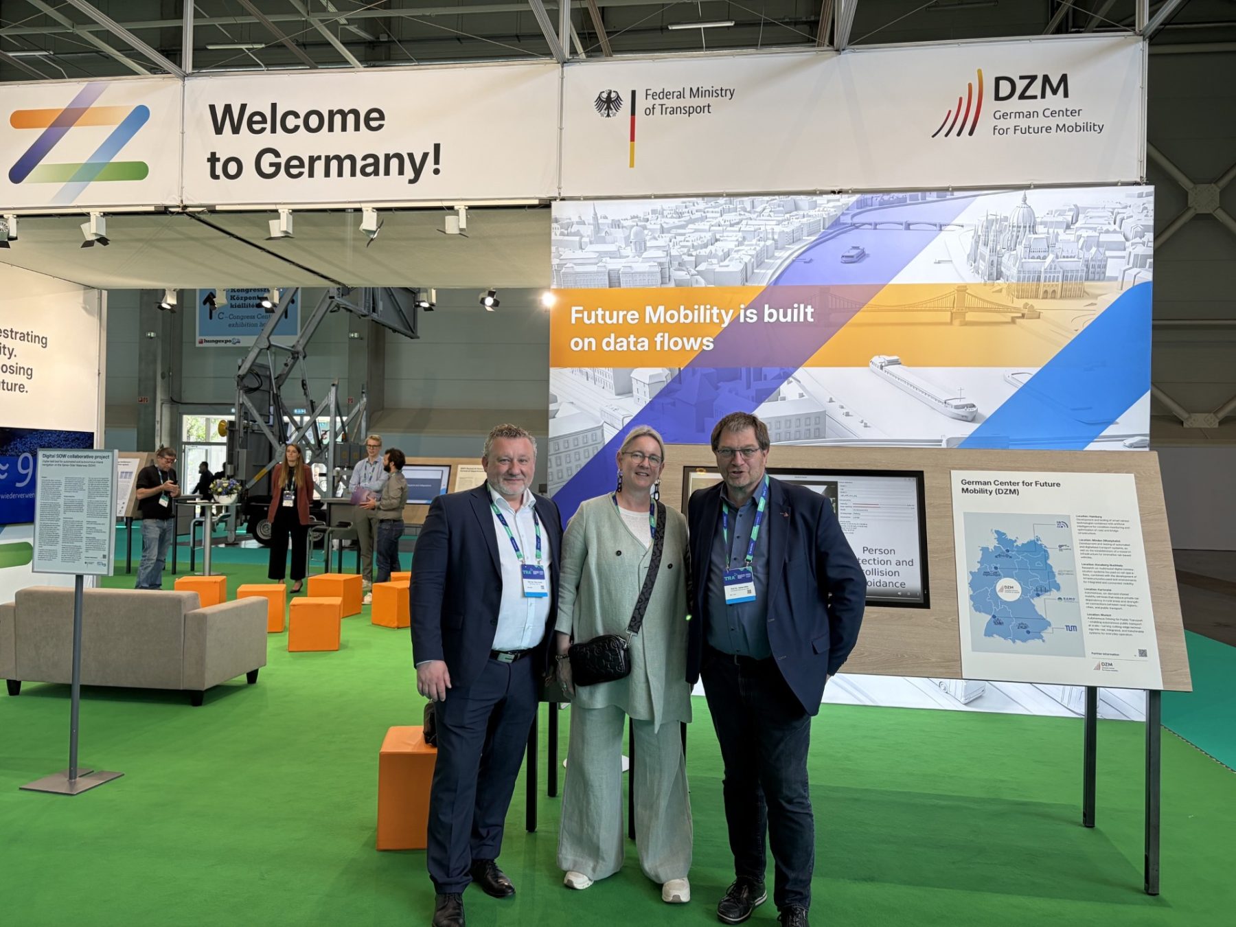 Drei Menschen posieren vor Messestand